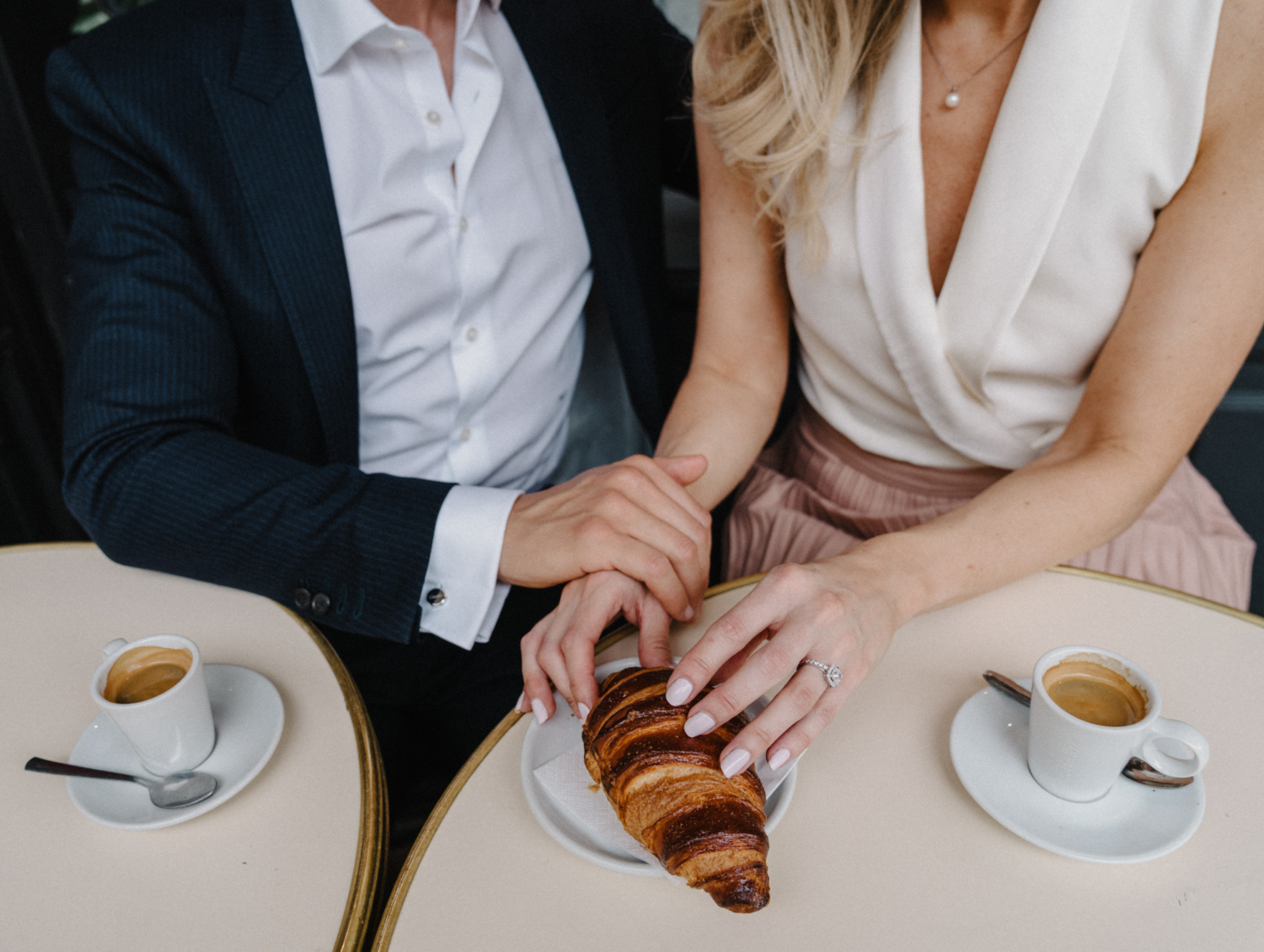 woman shows off engagement ring touching croissant in paris