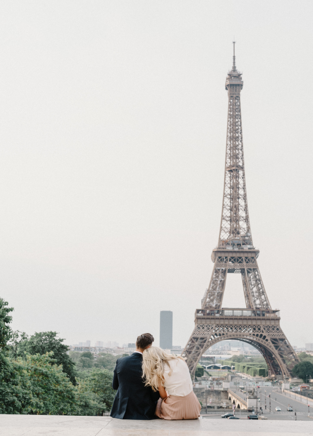 woman rests head on man's shoulder with view of eiffel tower