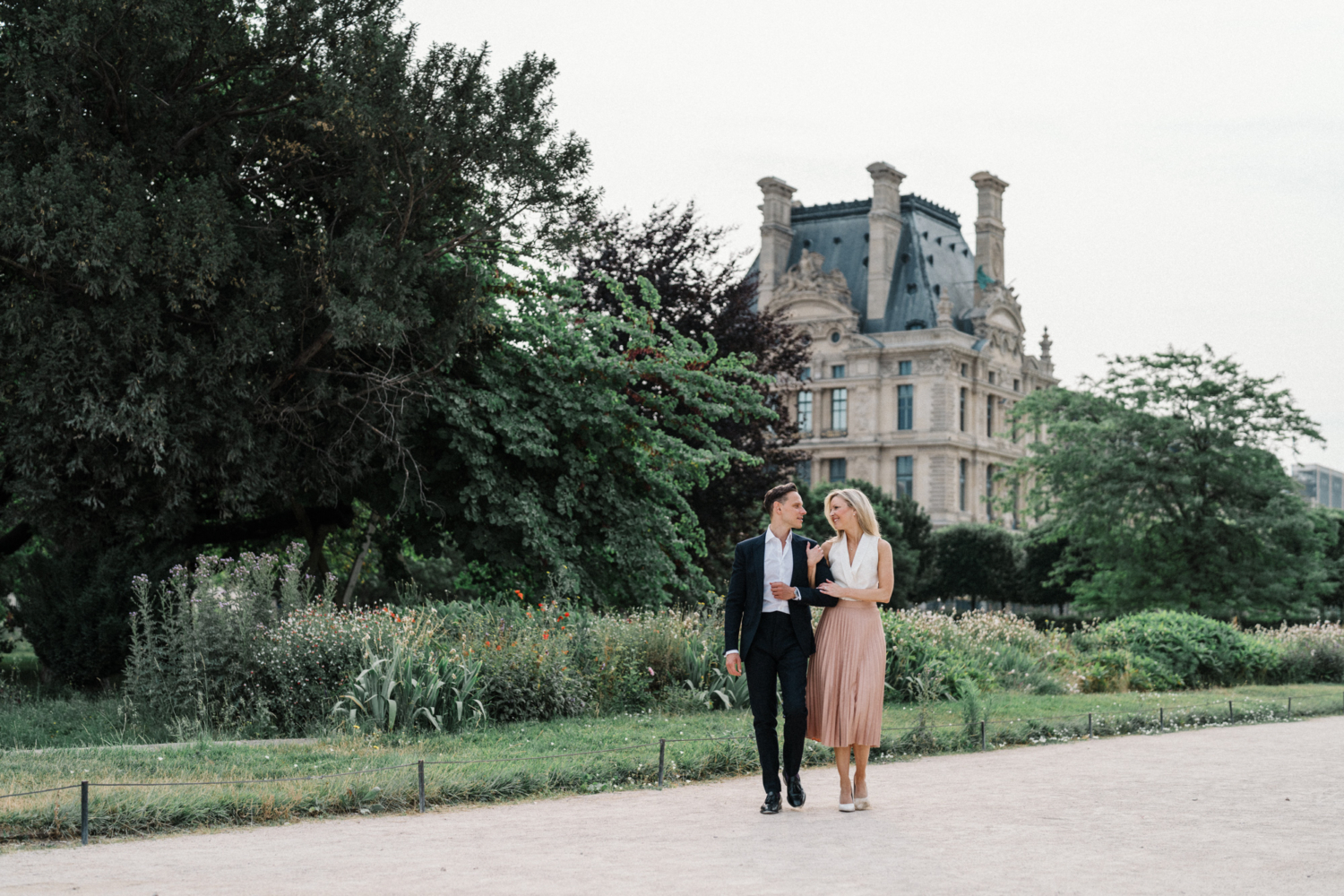 engaged couple walking arm in arm at tuileries gardens paris