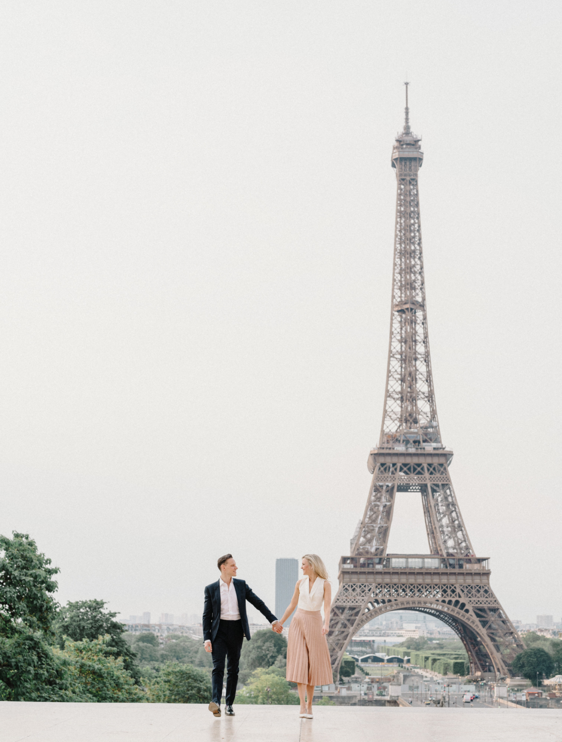 engaged couple walk at the eiffel tower in paris