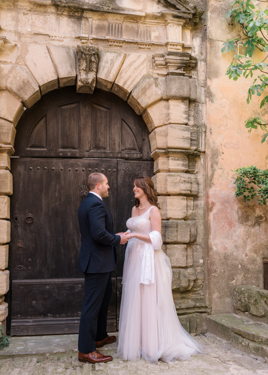 newly married couple laughing in front of old door