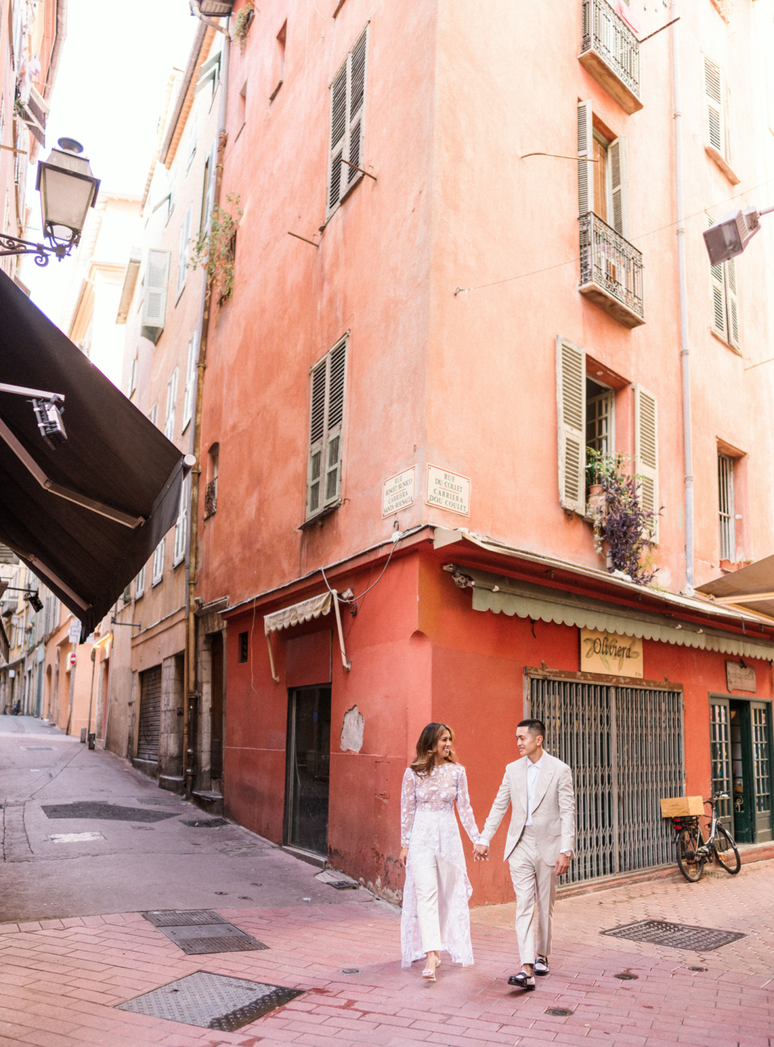 engaged couple walk in old town nice in front of orange building