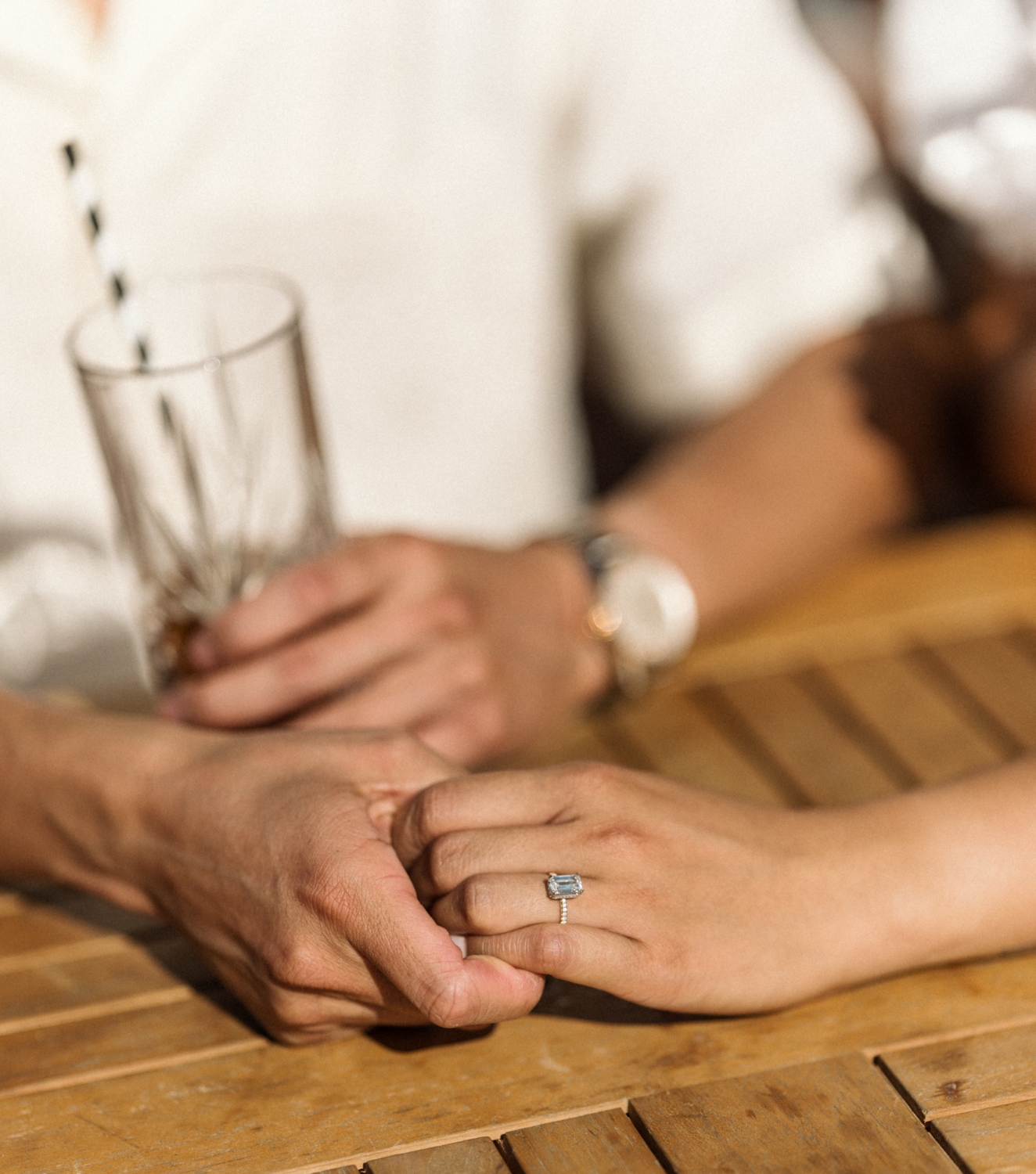 man holds woman's hand with diamond engagement ring