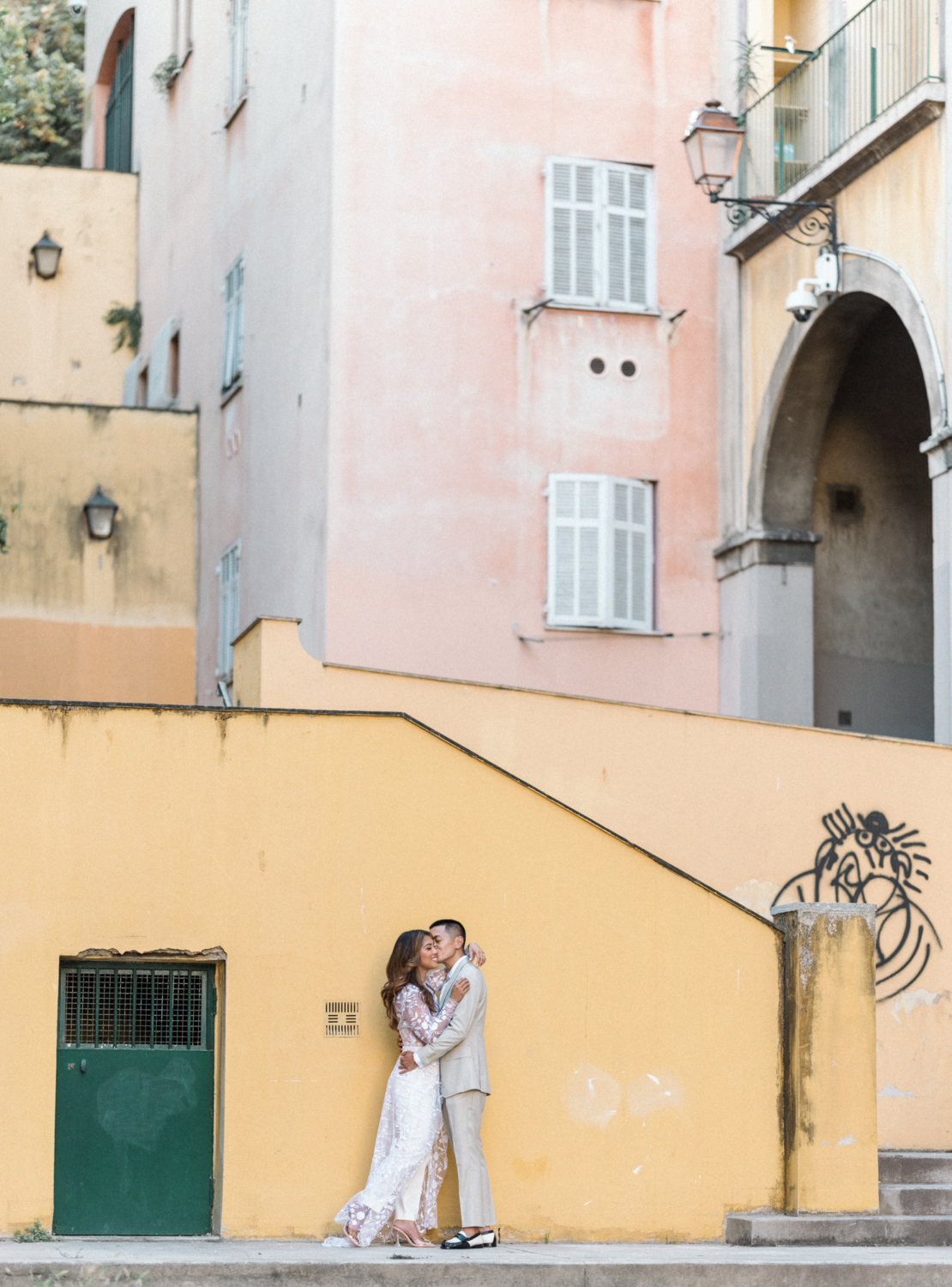 couple embrace standing next to yellow wall in nice france