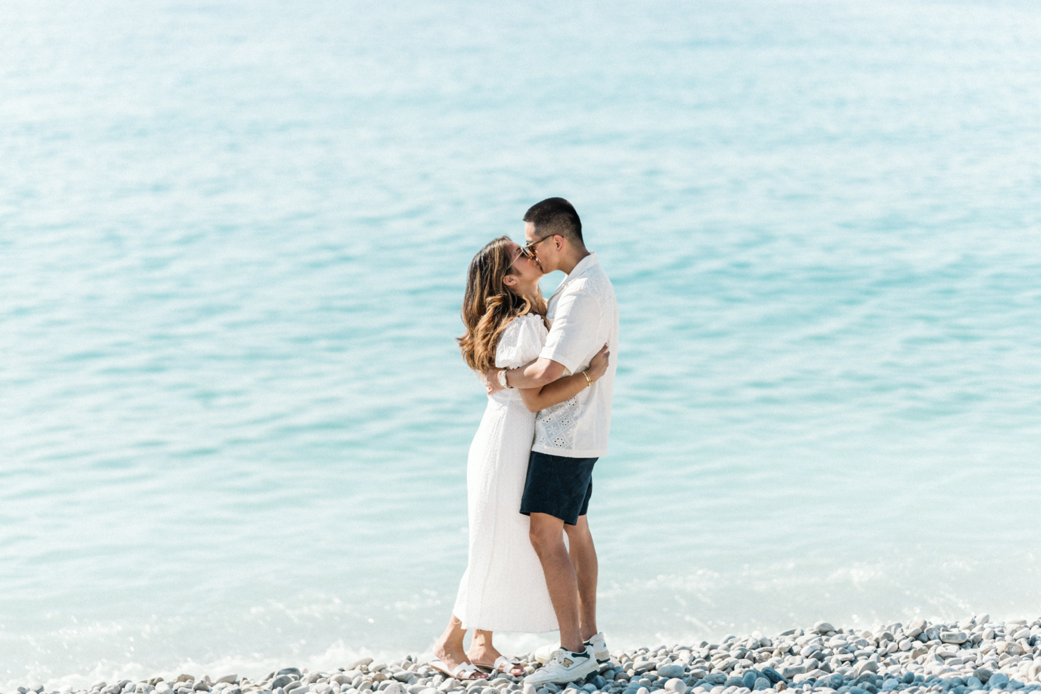 couple in sunglasses hug and kiss in the sea in nice france