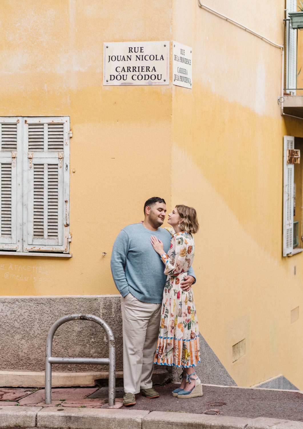 cute couple pose in front of yellow building