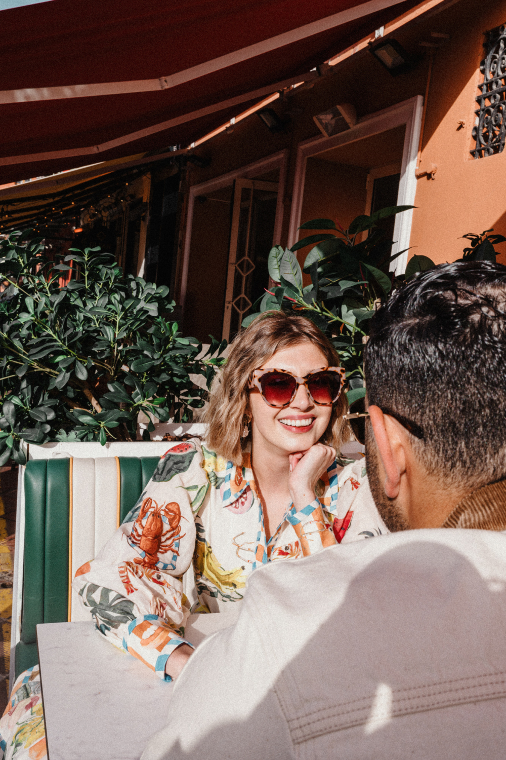 woman wears sunglasses and laughs at cafe in nice france