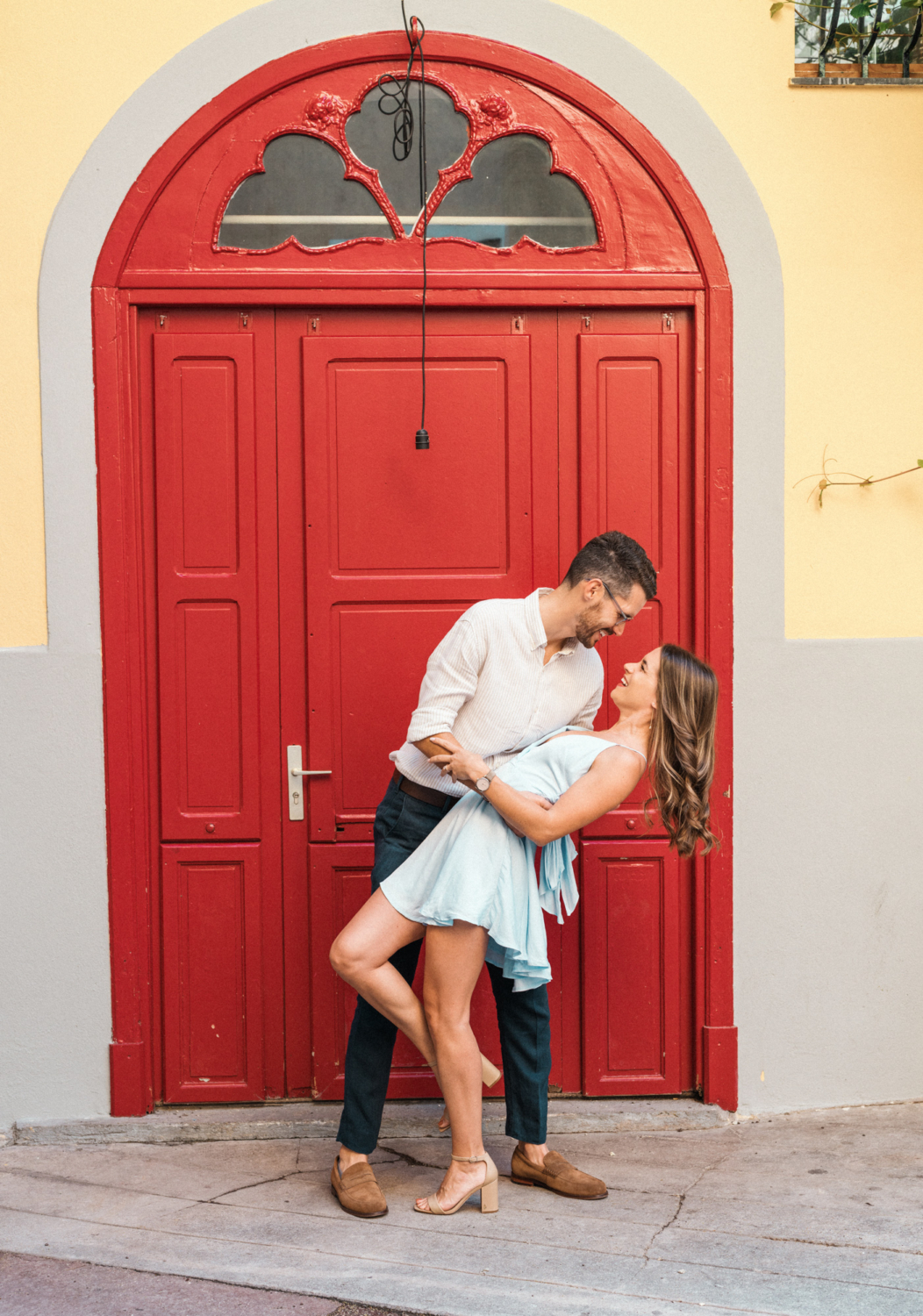 man dips woman backwards in front of red door in nice france