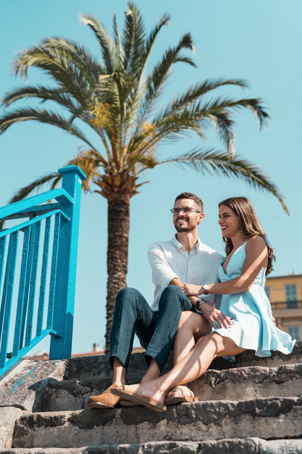 couple laugh on a staircase with palm tree in background