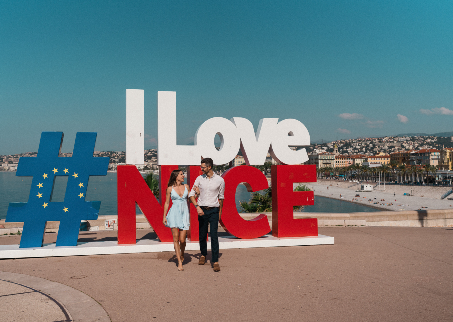 cute couple walking in front of i love nice sign