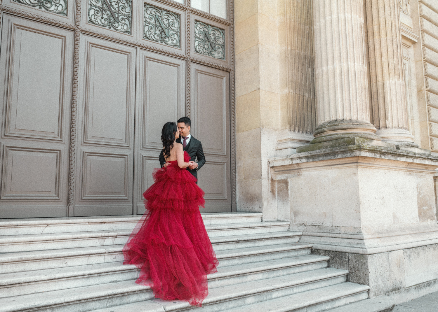 woman with long red gown poses on staircase in paris