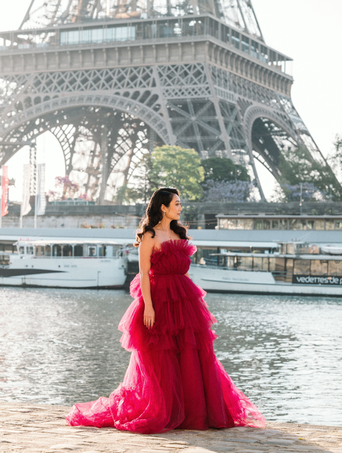 asian woman wearing long red gown poses at eiffel tower