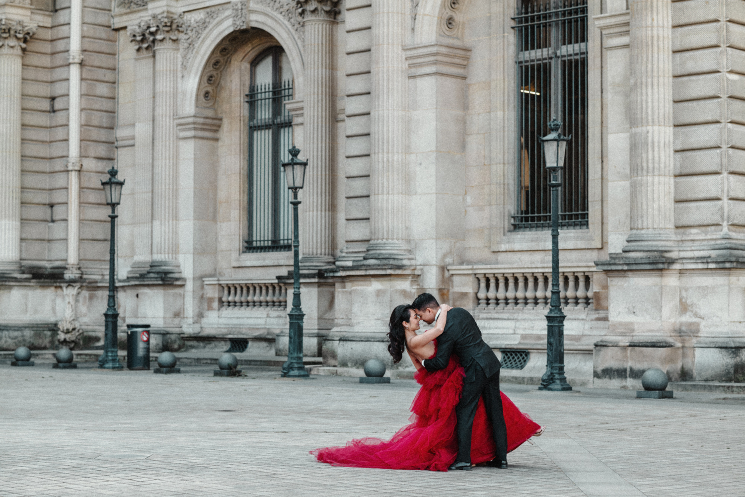 asian couple dance around courtyard at louvre museum paris