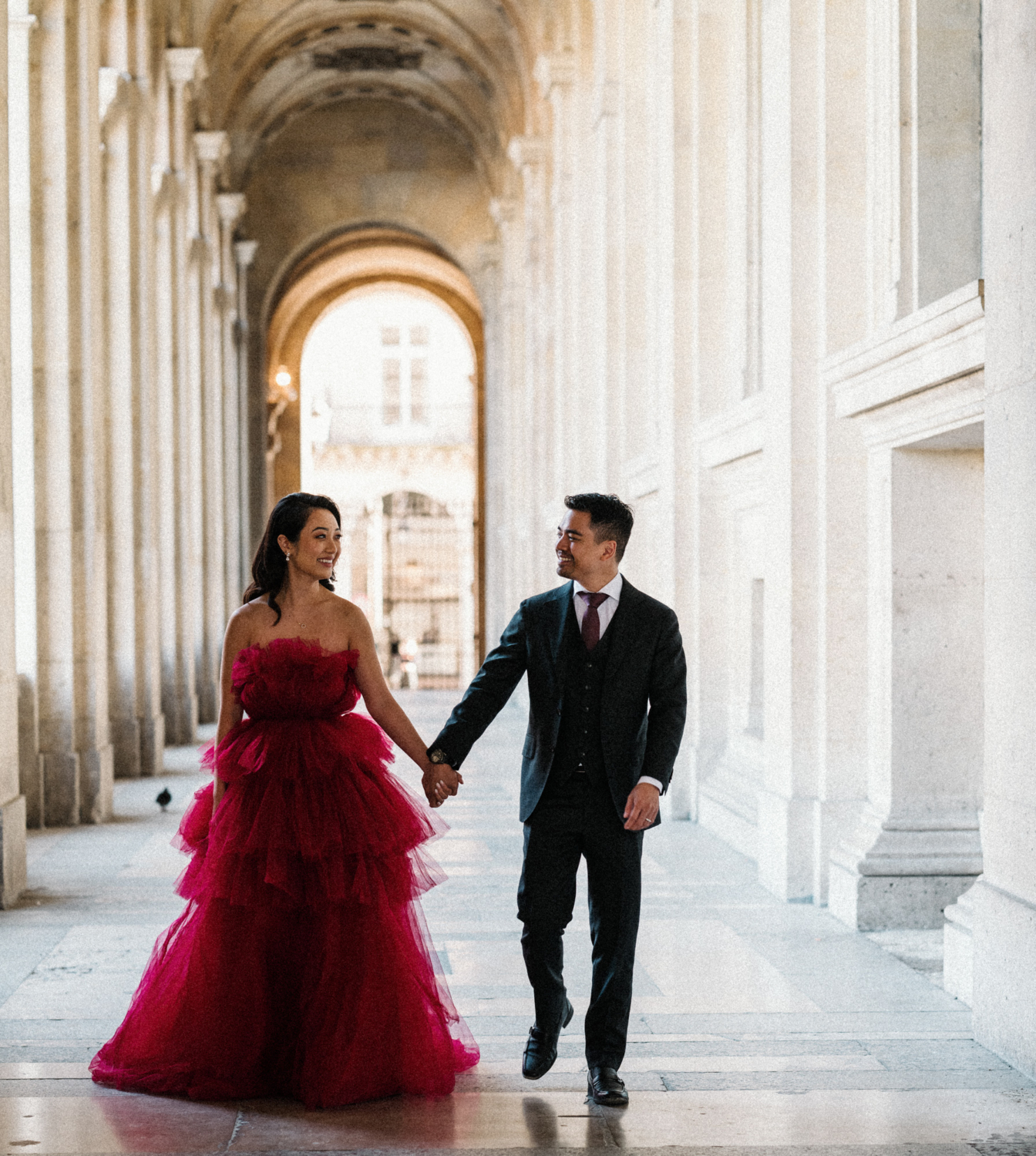 asian couple walk through corridor of louvre museum paris