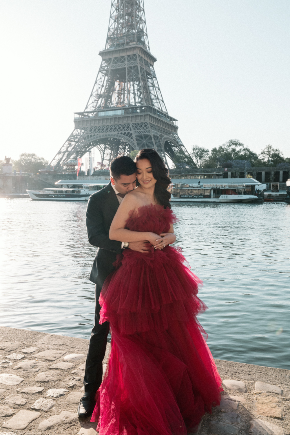 asian man kisses asian woman on shoulder with view of eiffel tower