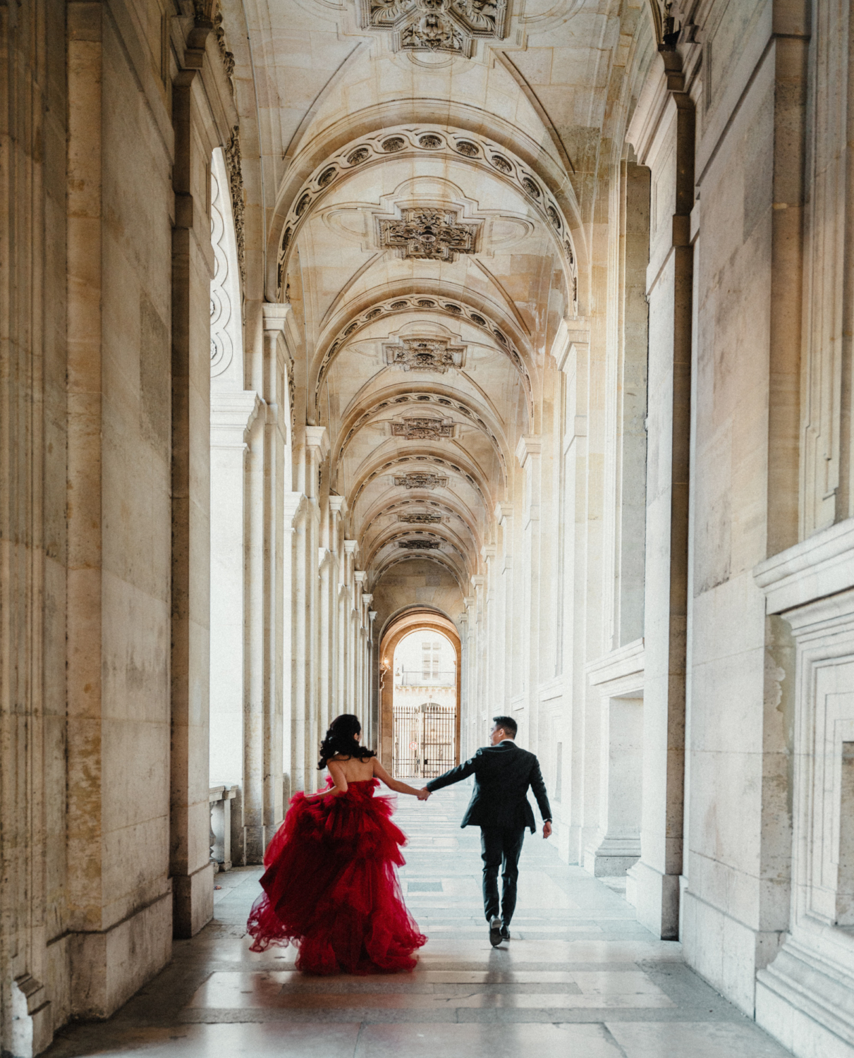 asian couple run through corridor at louvre museum paris