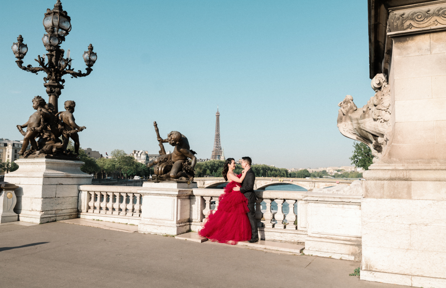 asian couple embrace on pont alexandre with view of eiffel tower