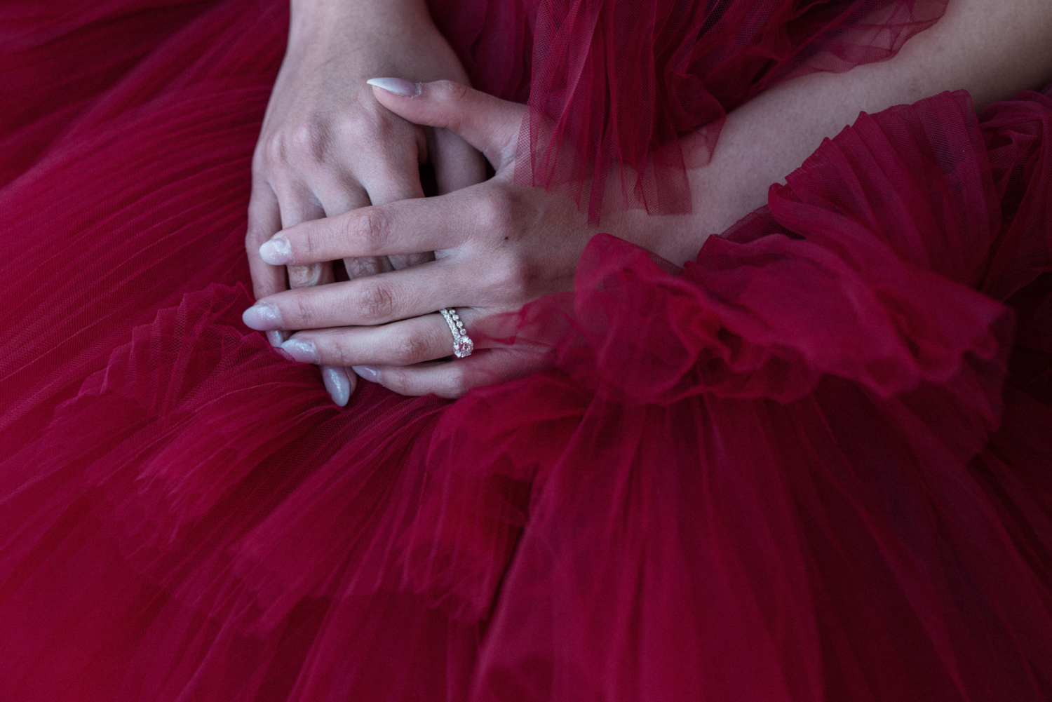 woman in red gowns hands with diamond wedding ring