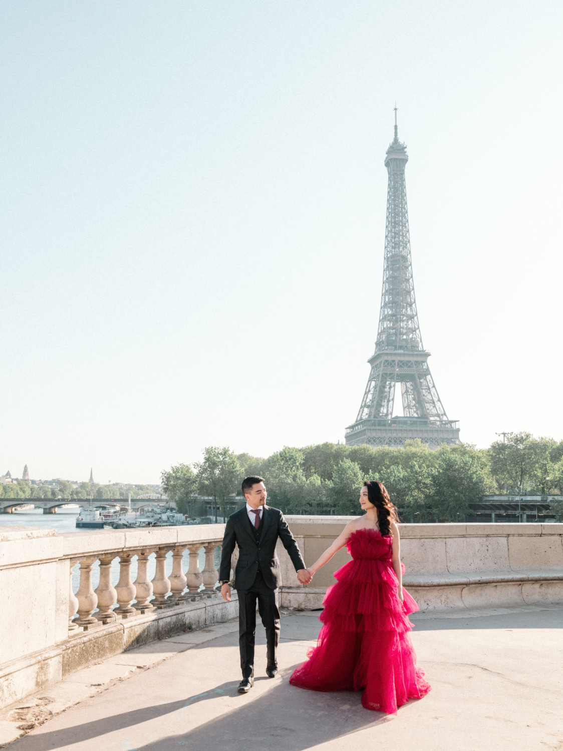 asian couple walk hand in hand with view of eiffel tower