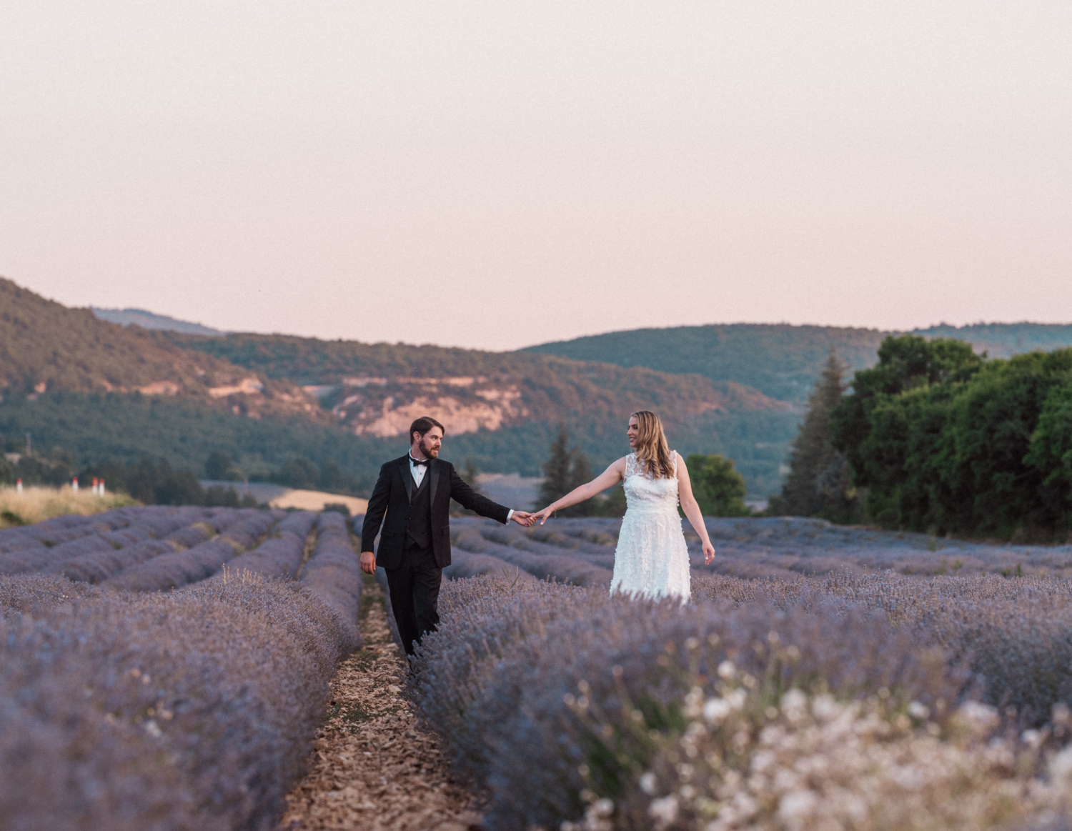 bride and groom holding hands in a lavender field