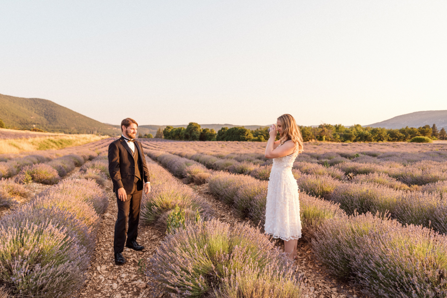 bride takes a photo of groom in lavender fields