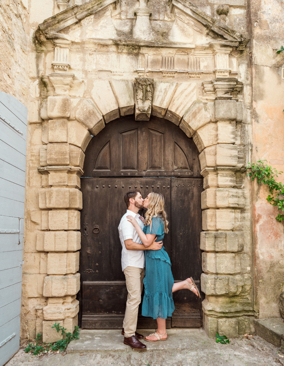 engaged couple kiss next to an old door in france