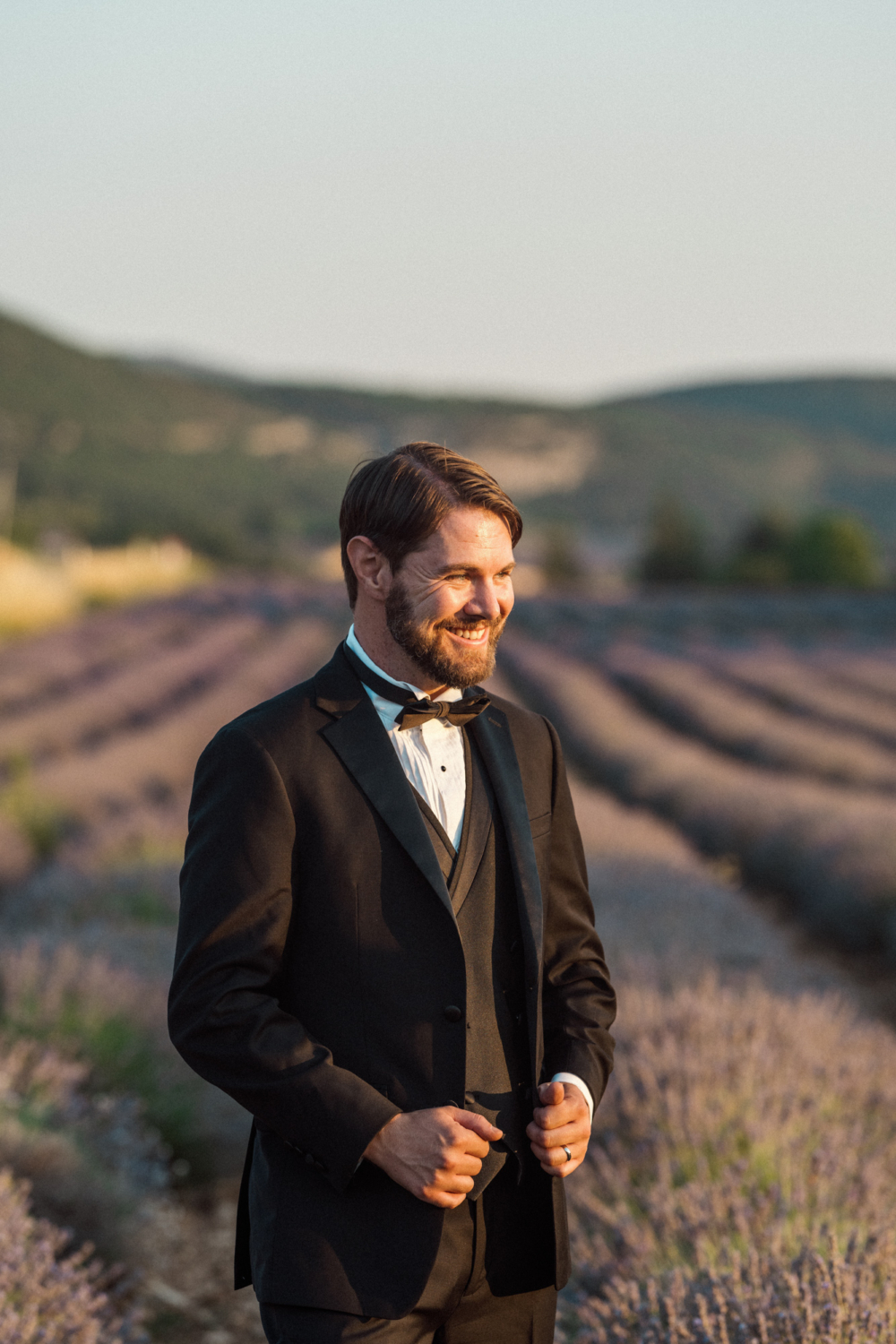 handsome groom posing in a tux in a lavender field