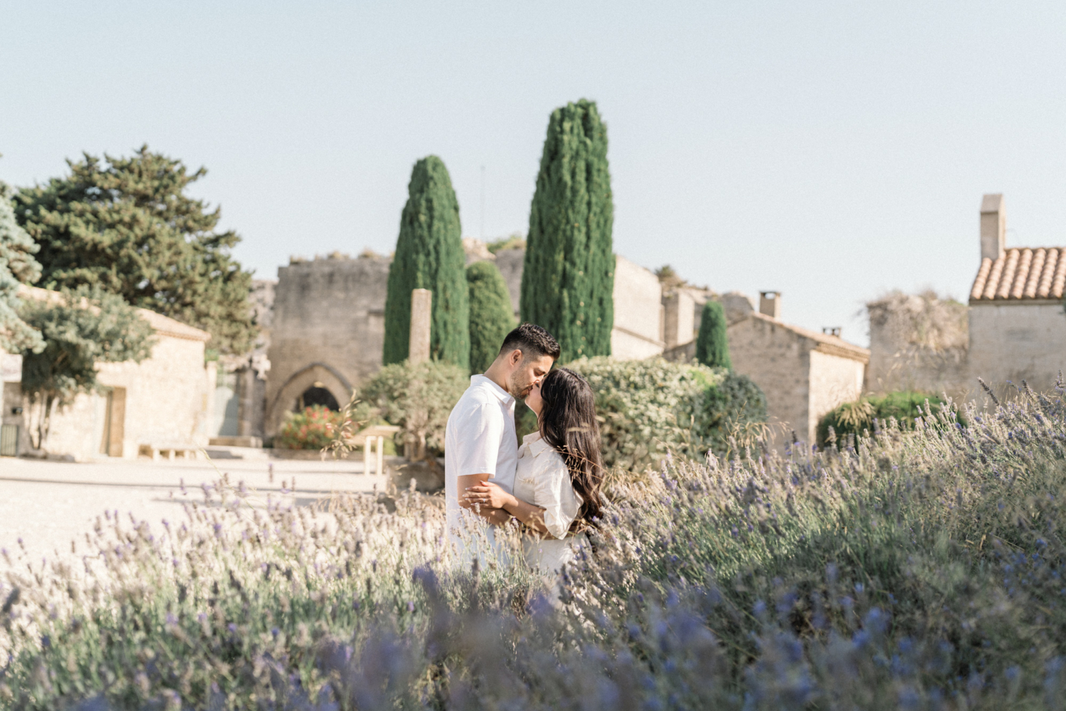newly engaged couple kiss beneath flowers in les baux de provence
