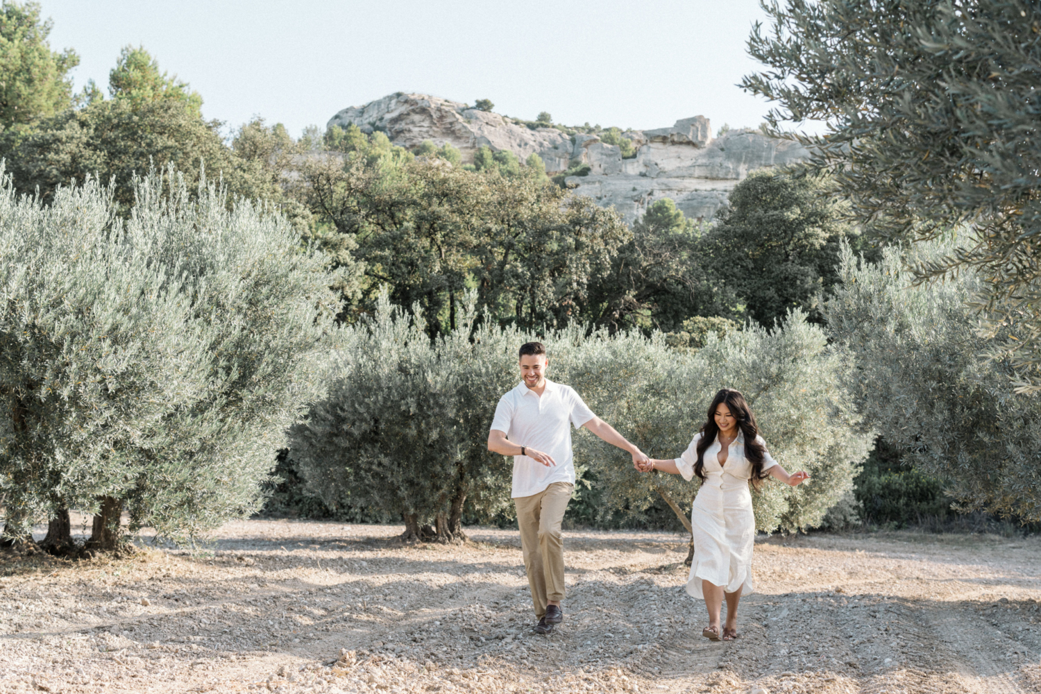 engaged couple walk through olive groves in les baux de provence