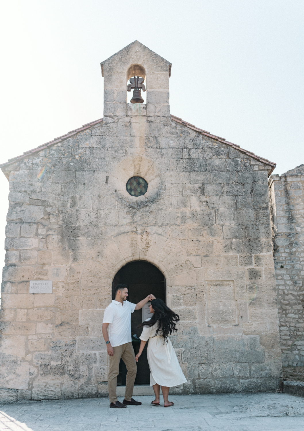 engaged couple dance in front of chapel in les baux de provence
