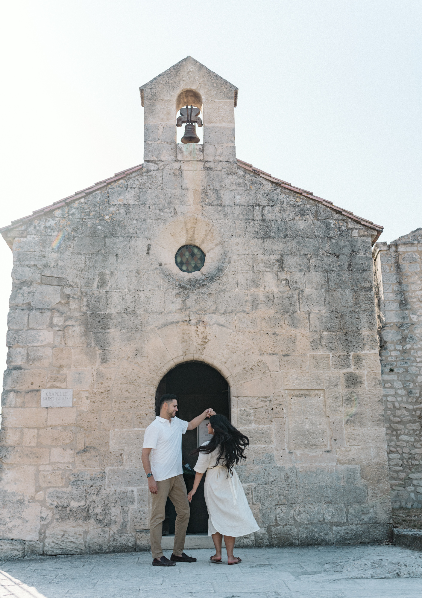 engaged couple dance in front of chapel in les baux de provence during Engagement Photos In Provence