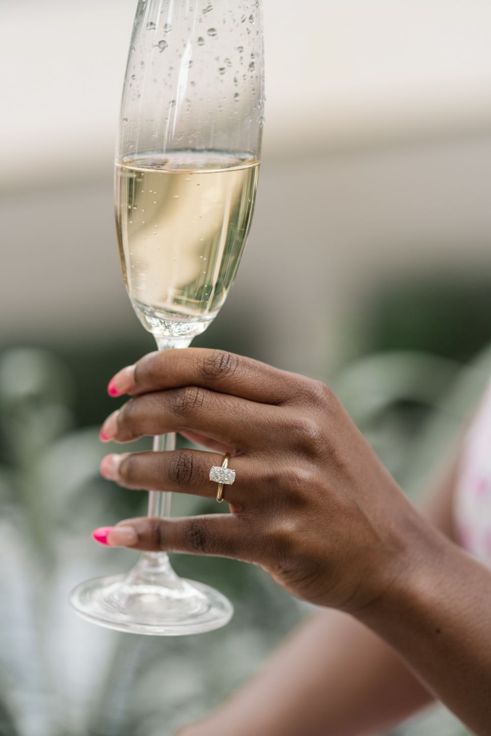 woman holds champagne flute wearing diamond ring