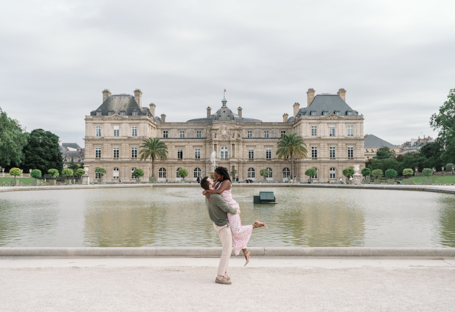 man lifts woman in air in luxembourg gardens paris