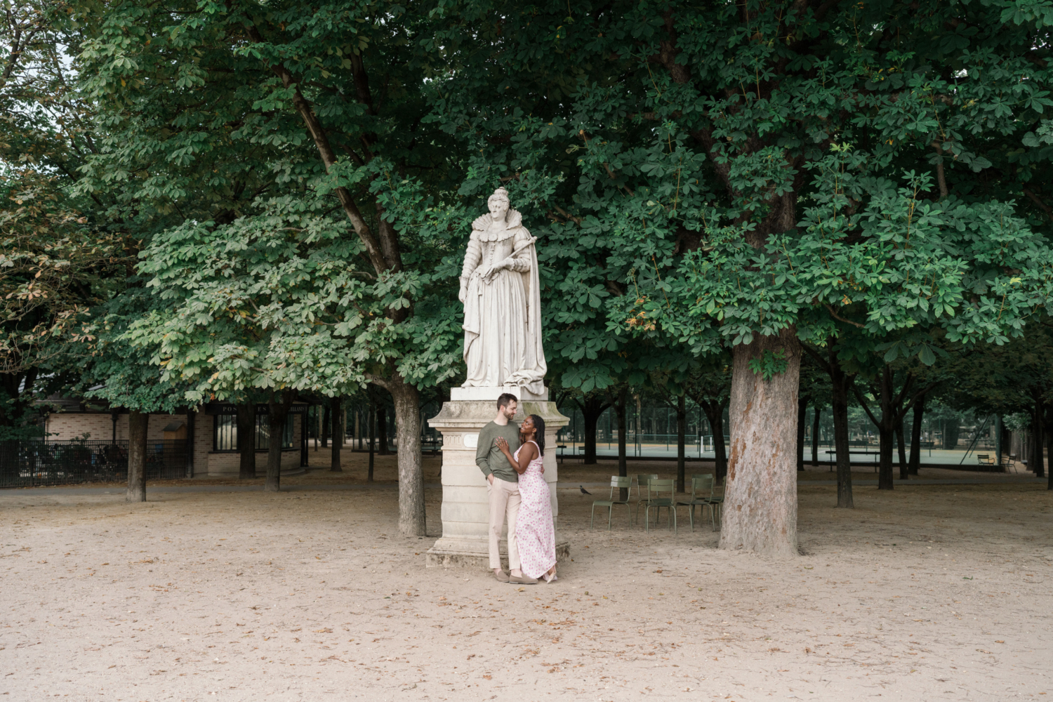 young couple pose in front of statue in luxembourg gardens paris