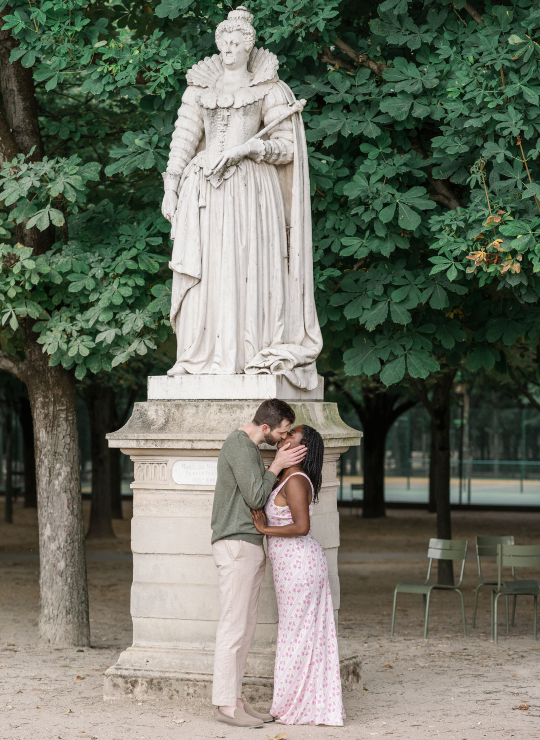 newly engaged couple kiss in front of statue in luxembourg gardens paris