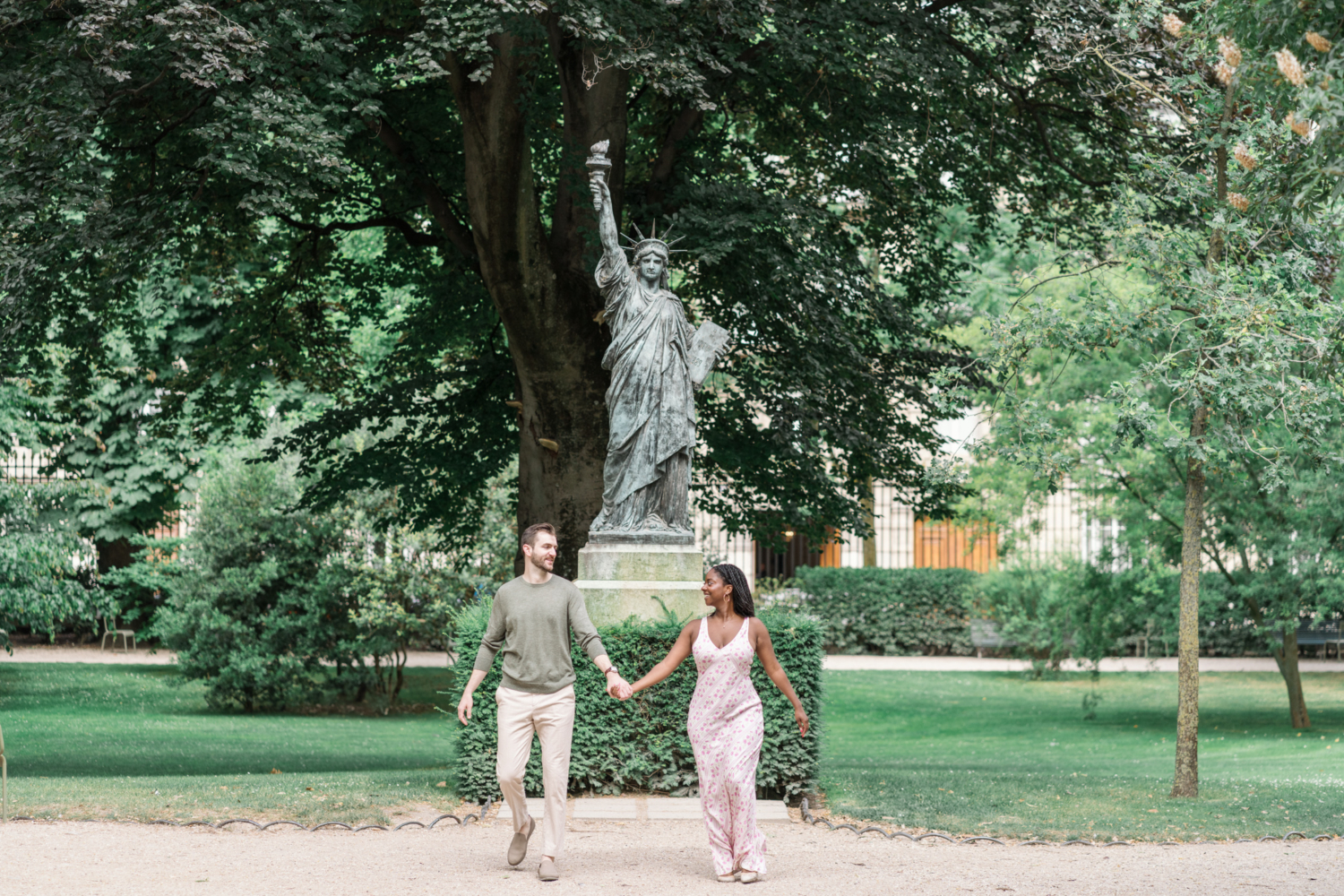 newly engaged couple walk near statue of liberty in luxembourg gardens paris