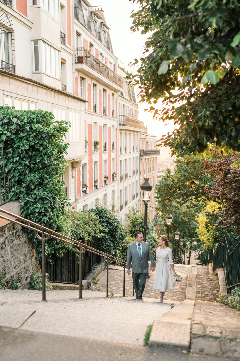 newlyweds walk up staircase in montmartre paris