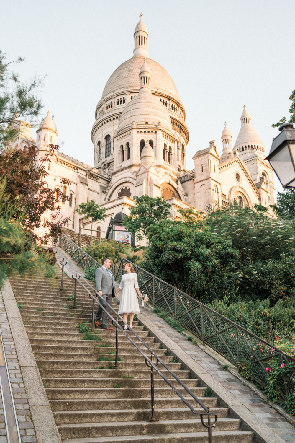 newlyweds walk down stairs at sacre coeur basilica paris