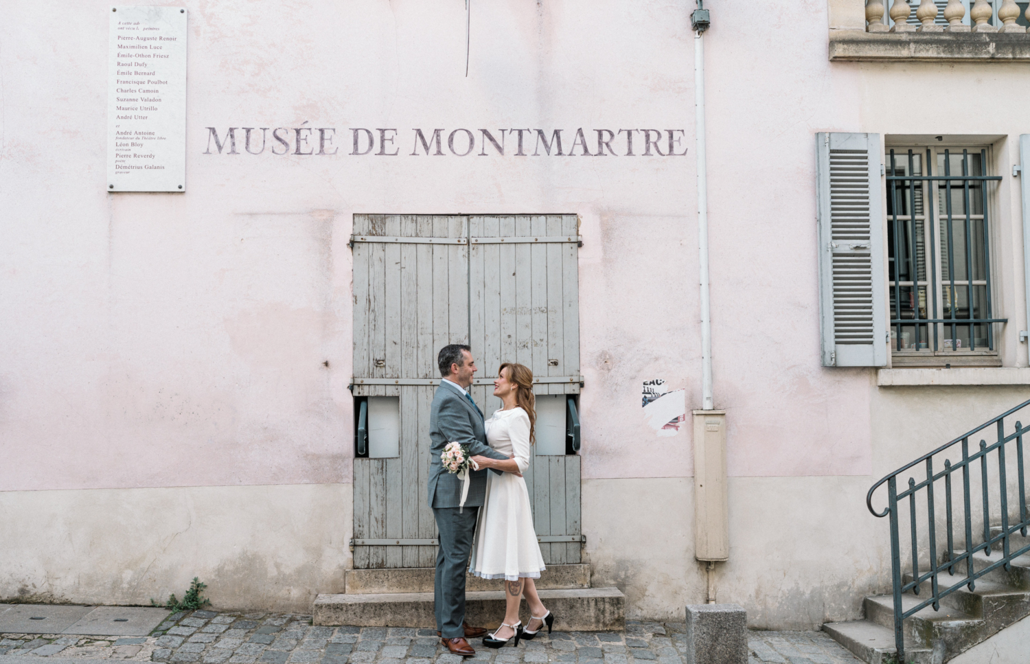 newlyweds pose in front of musee de montmartre paris