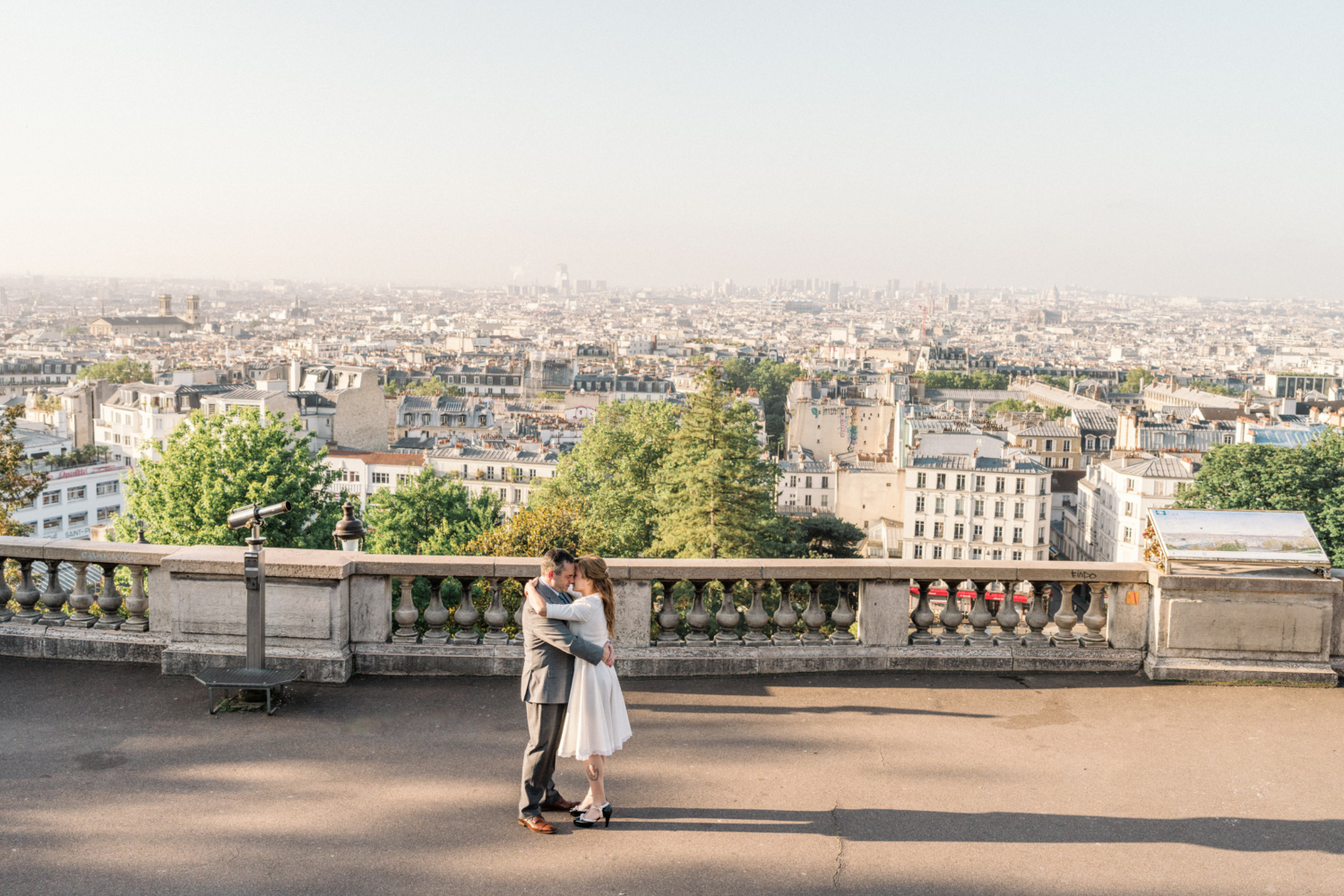 newlyweds embrace with view of paris from montmartre