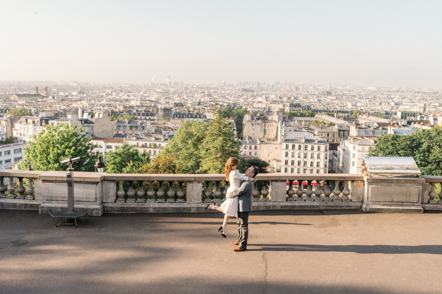 man lifts woman in air with view of paris