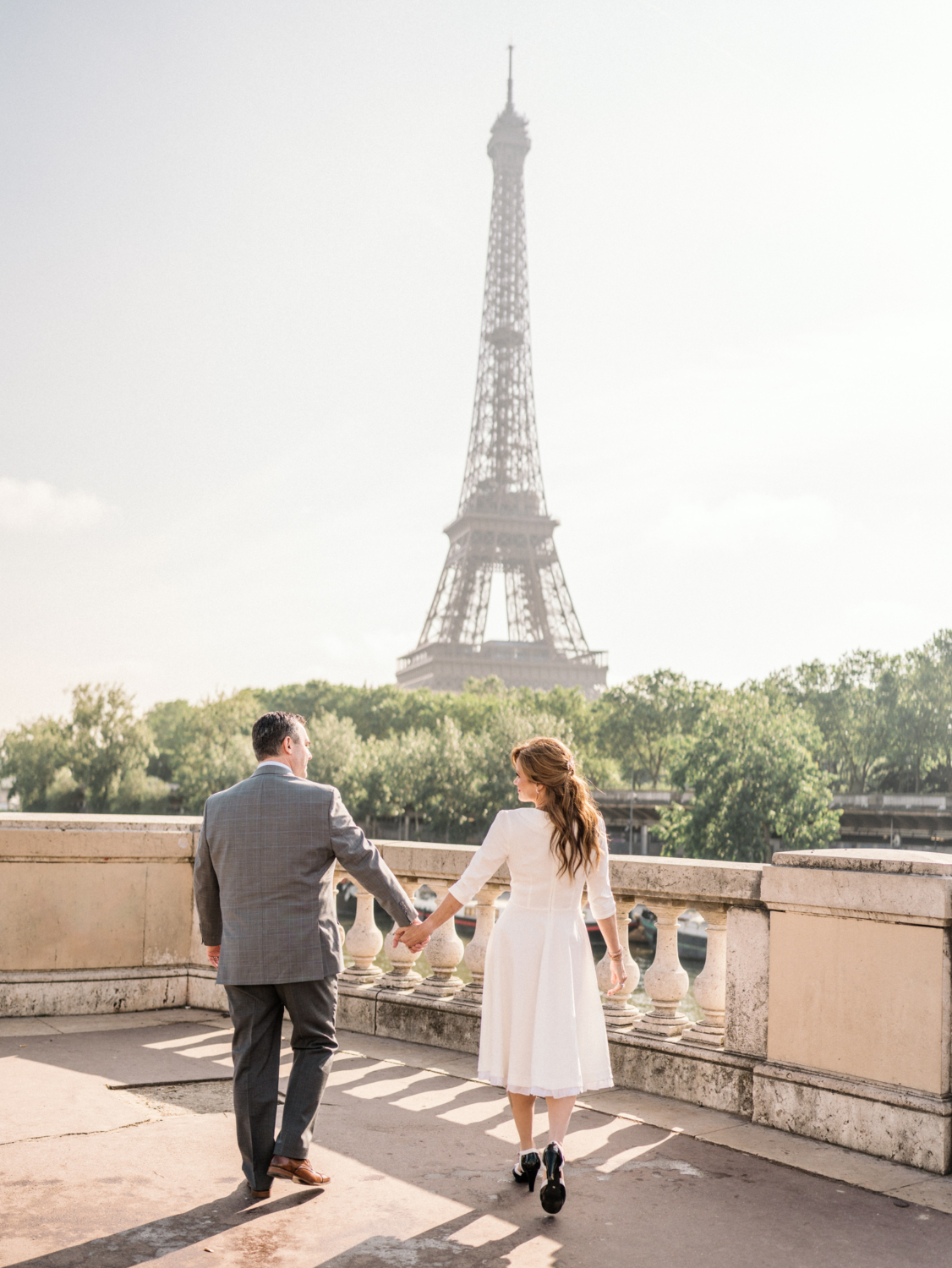 newlyweds walking hand in hand at the eiffel tower