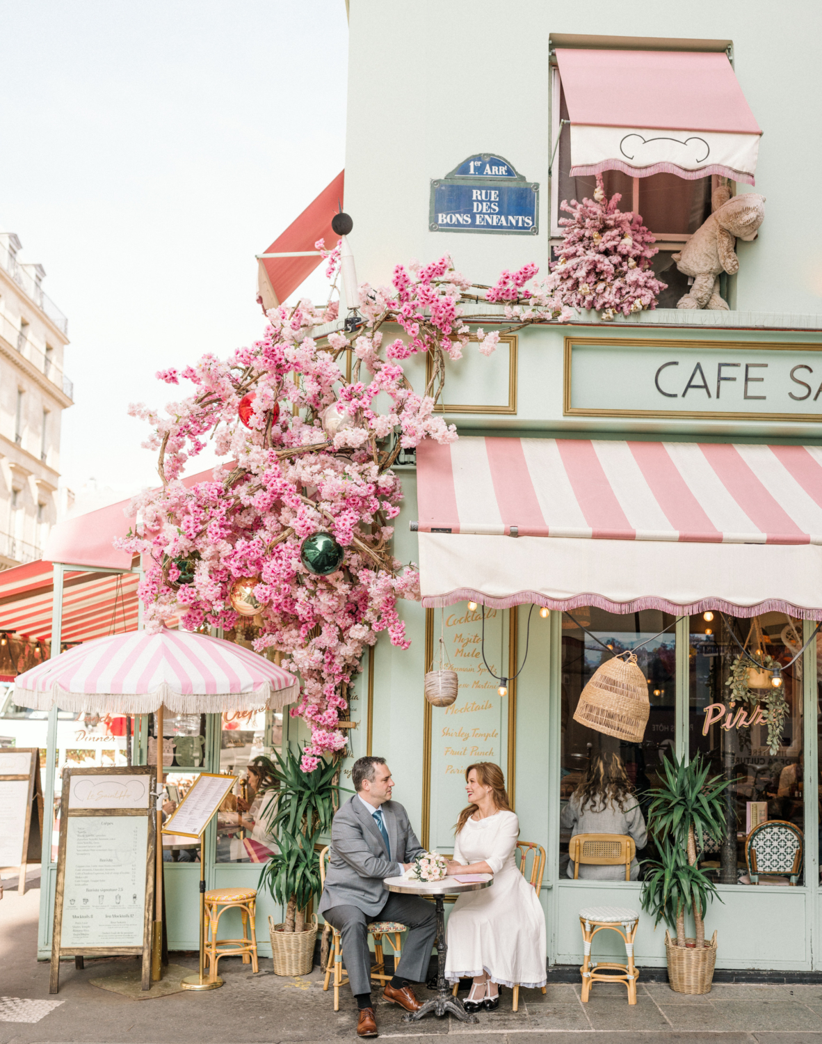 newlyweds sitting in front of colorful cafe in paris