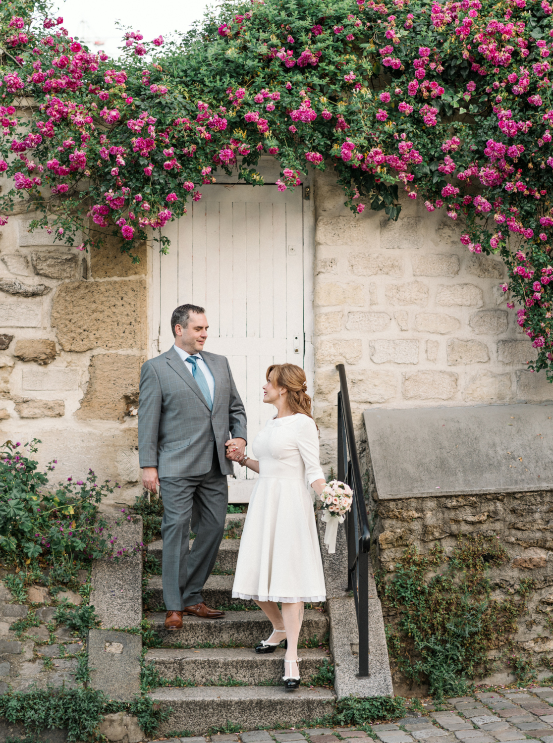 newlyweds walk under flower canopy in paris