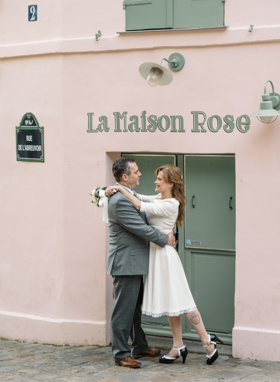 newlyweds embrace in front of famous pink restaurant in paris