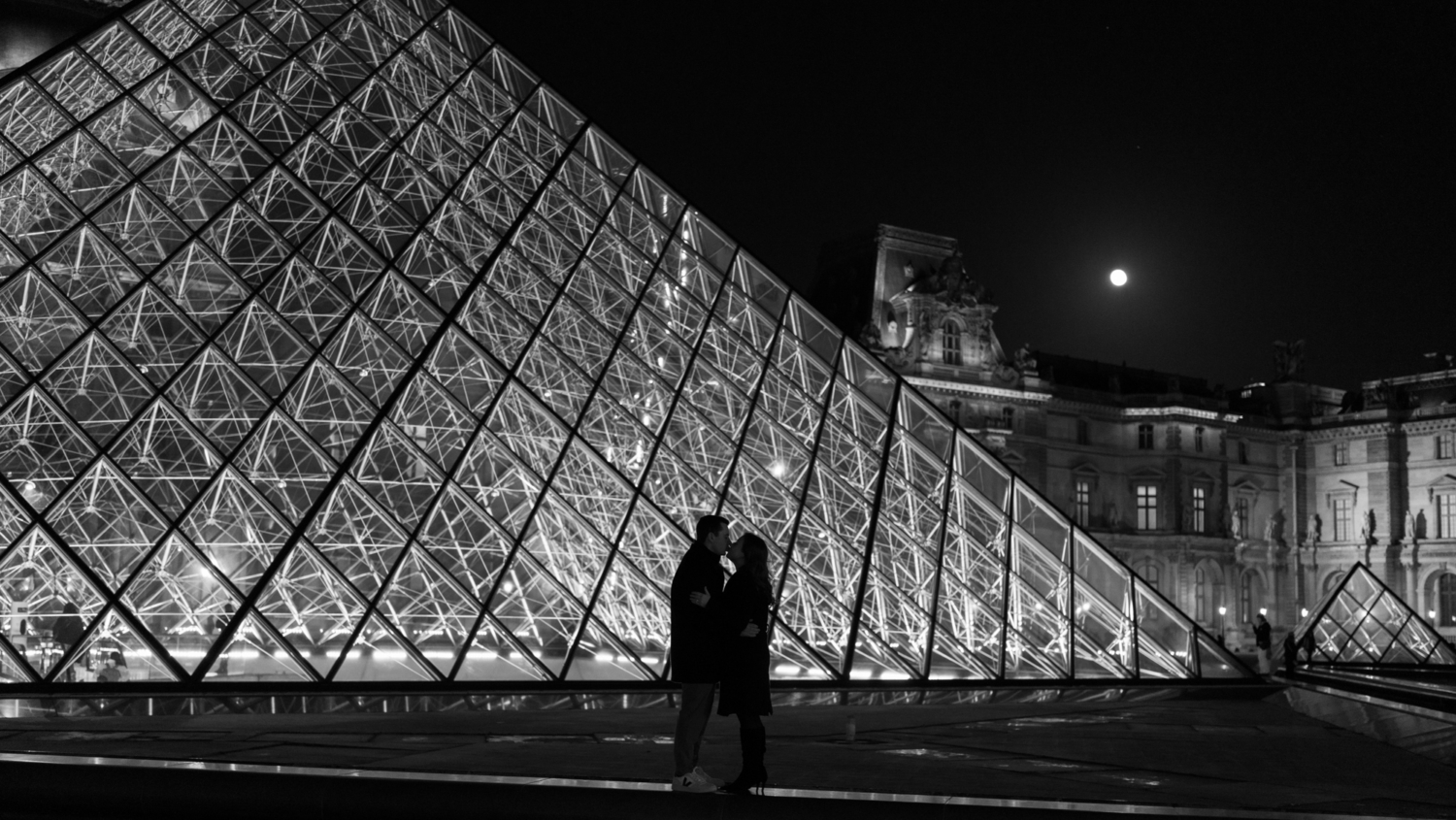 engaged couple kiss at night at the louvre paris