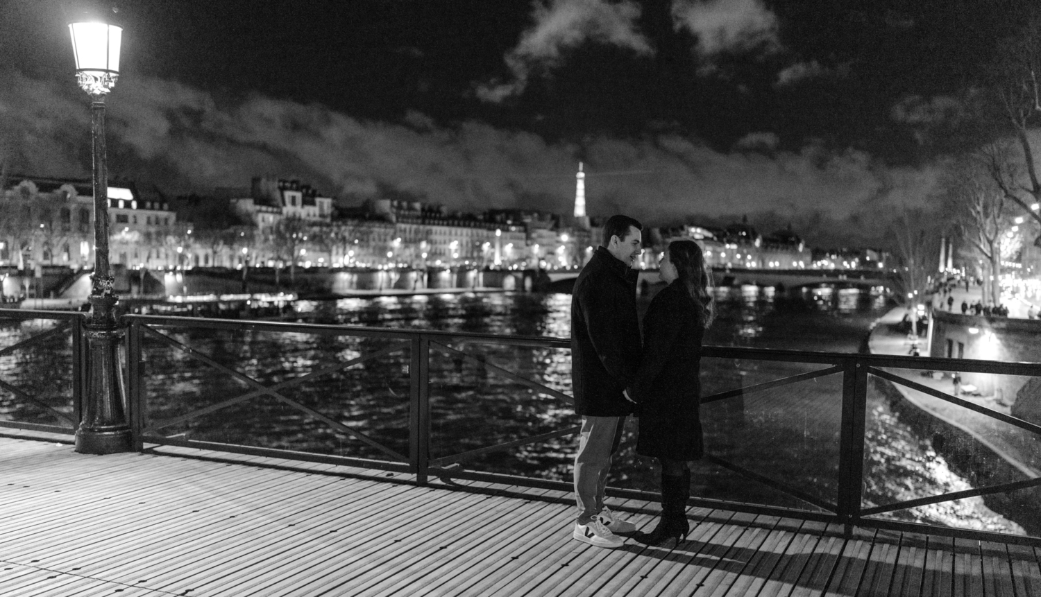 engaged couple hold hands on pont des arts at night