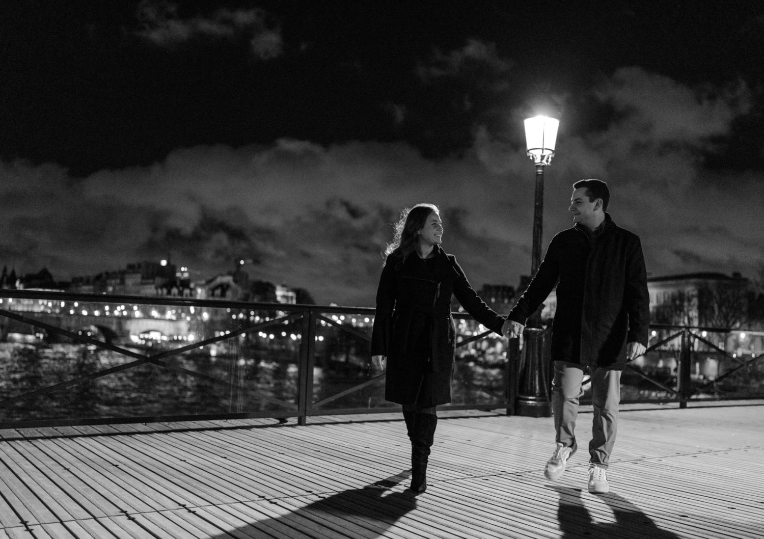 engaged couple walk hand in hand and smile on pont des arts in paris