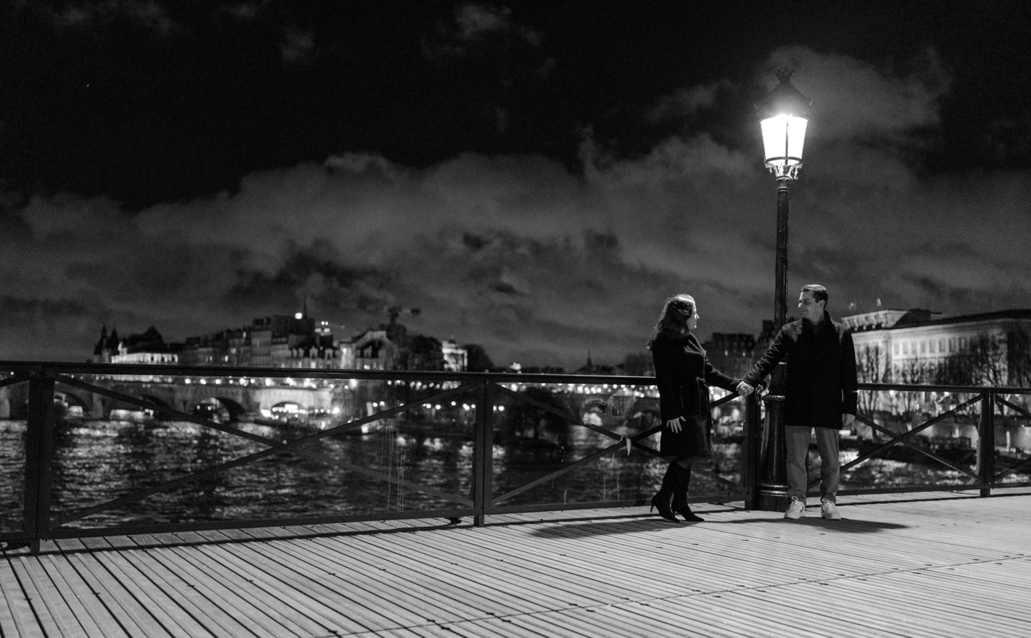 couple hold hands on pont des arts in paris at night