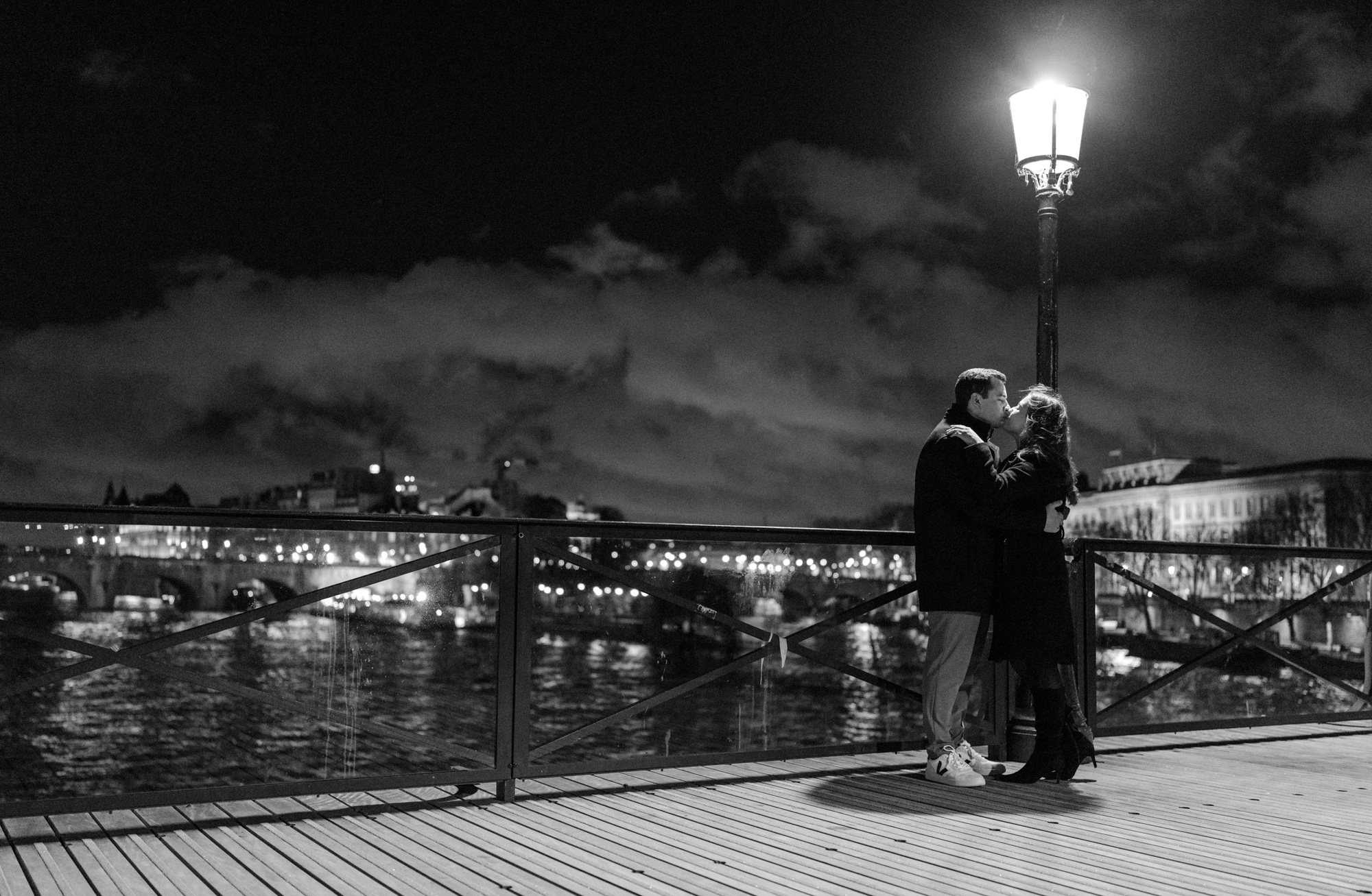 engaged couple kiss under street lamp on pont des arts in paris